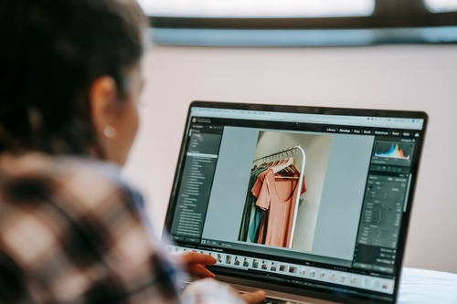 Woman editing a clothing product photo on a laptop 